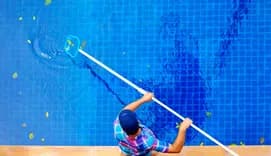 Young adult man, personnel cleaning the pool from leaves