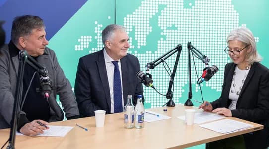 Three people in a podcast studio setting talking with micriphones