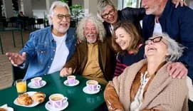 Cheerful group of mature people laughing sitting at cafeteria bar table
