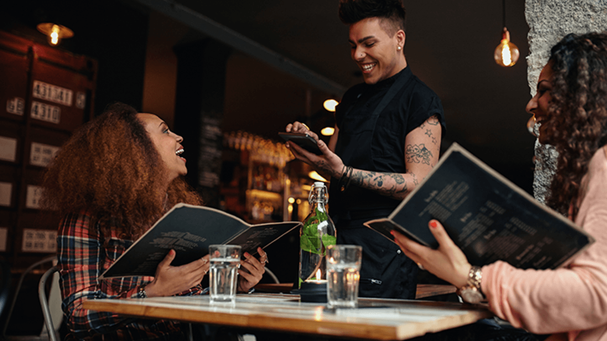 Image of young women placing an order to a waiter in a cafe