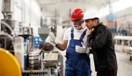 Colleagues with helmets working in factory