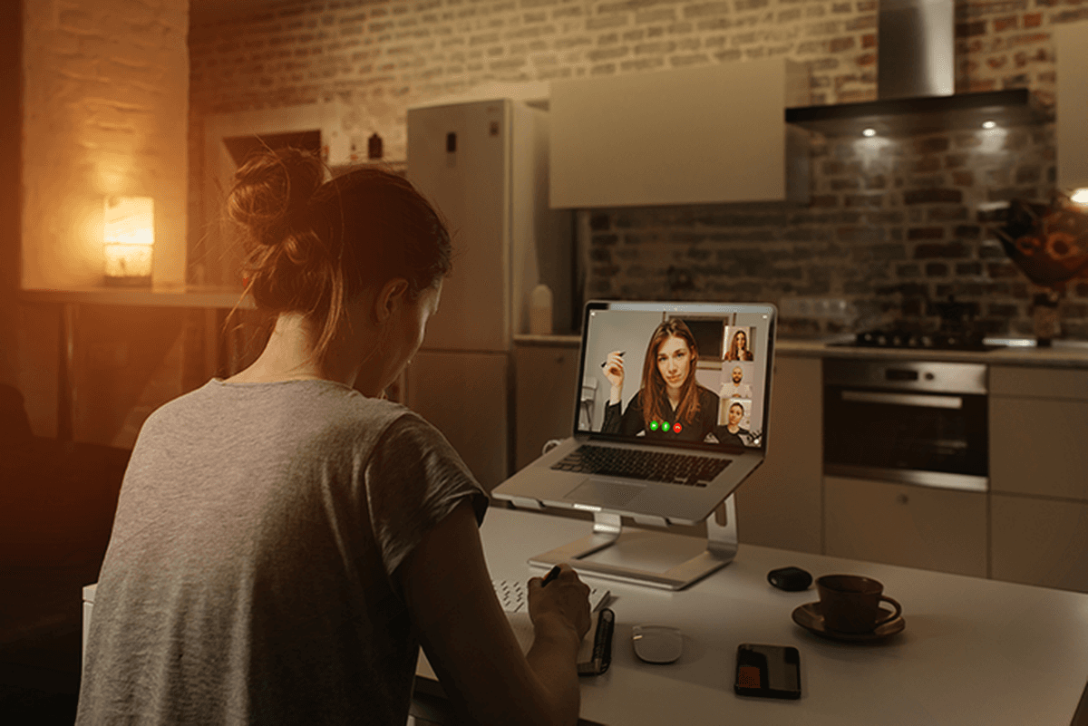 Female teleworker taking notes during video conference on her laptop