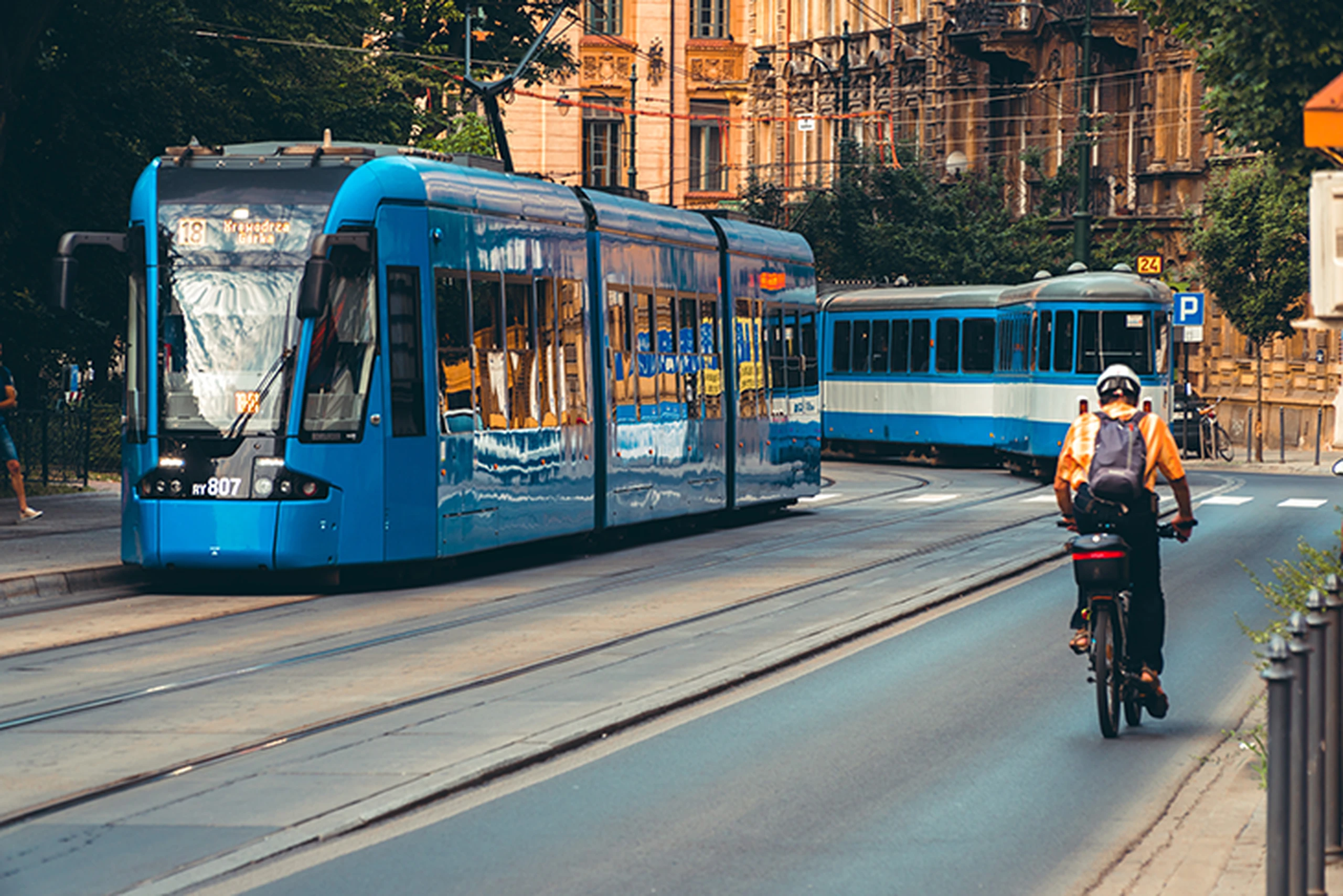 Image of people waiting for tram in city street and man cycling on cycle path