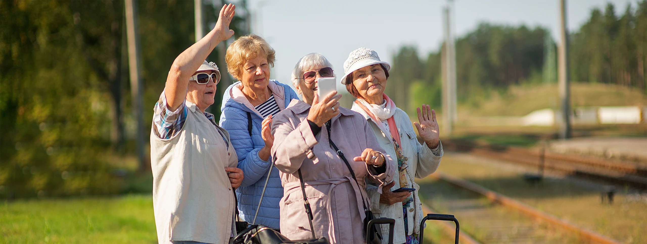 Group of elderly women taking a selfie while waiting on a platform for a train
