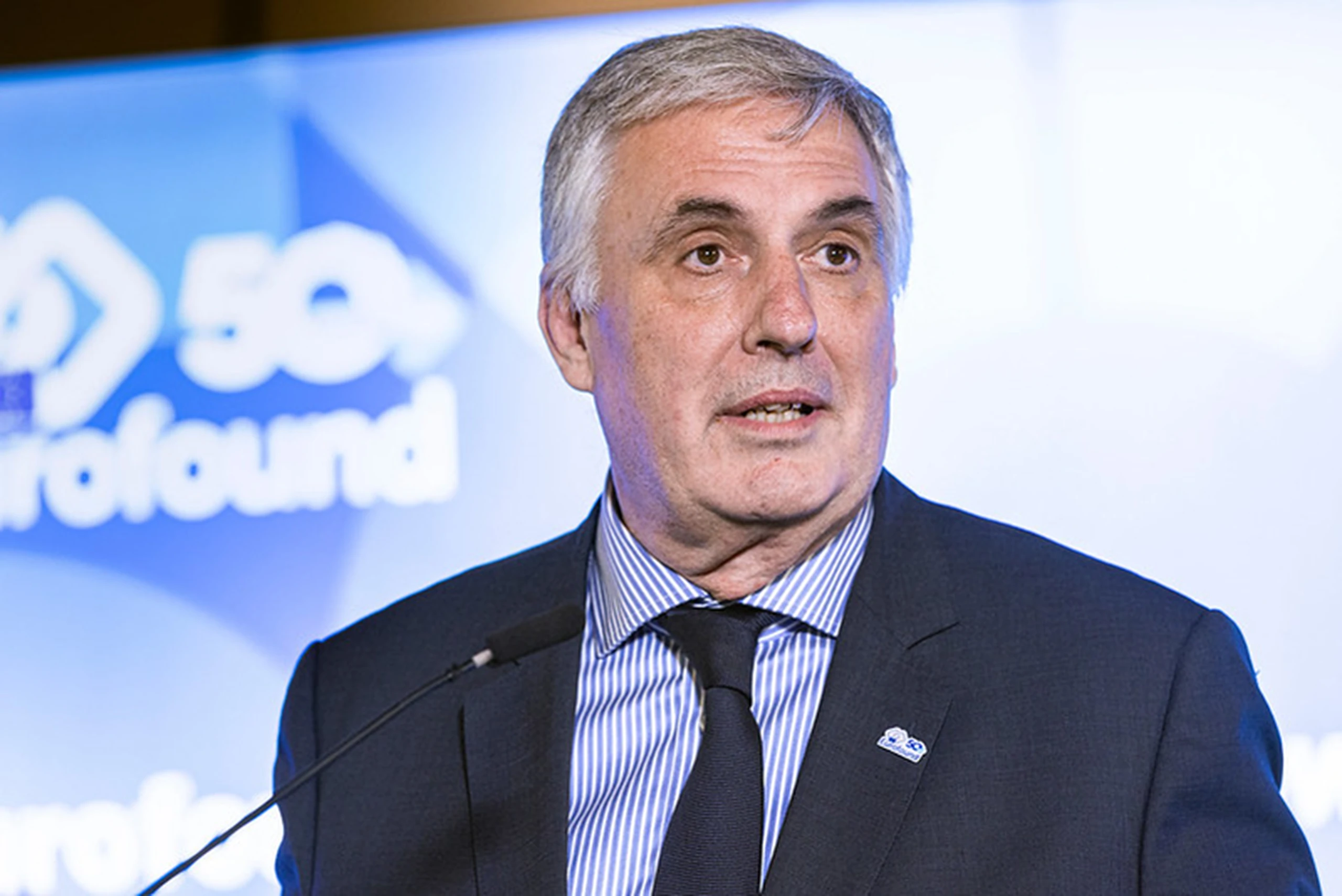 Man in suit in front of Eurofound 50 logo speaking in microphone