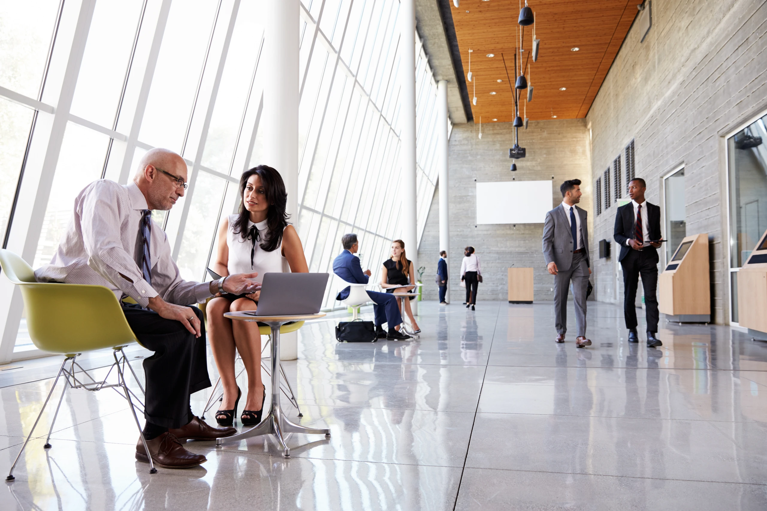 Workers meeting in office foyer and others leaving the office - by Monkey Business / Adobe Stock