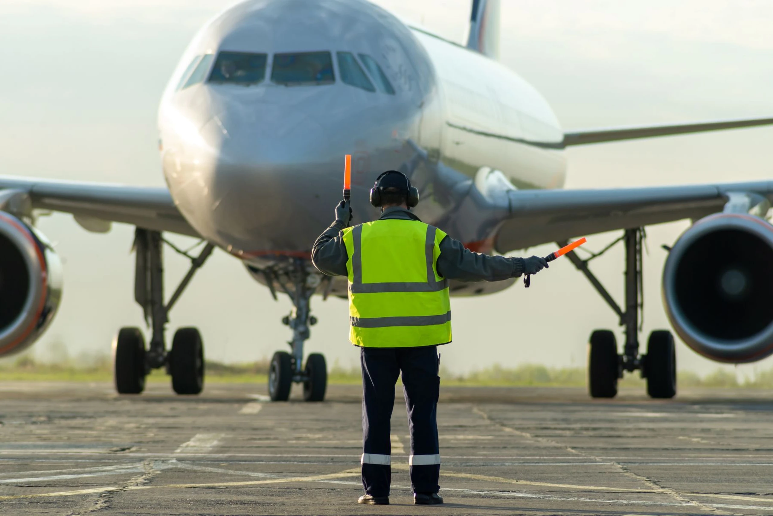 Ground crew signaling to airplane on approach to gate by Vitaliy / Adobe Stock