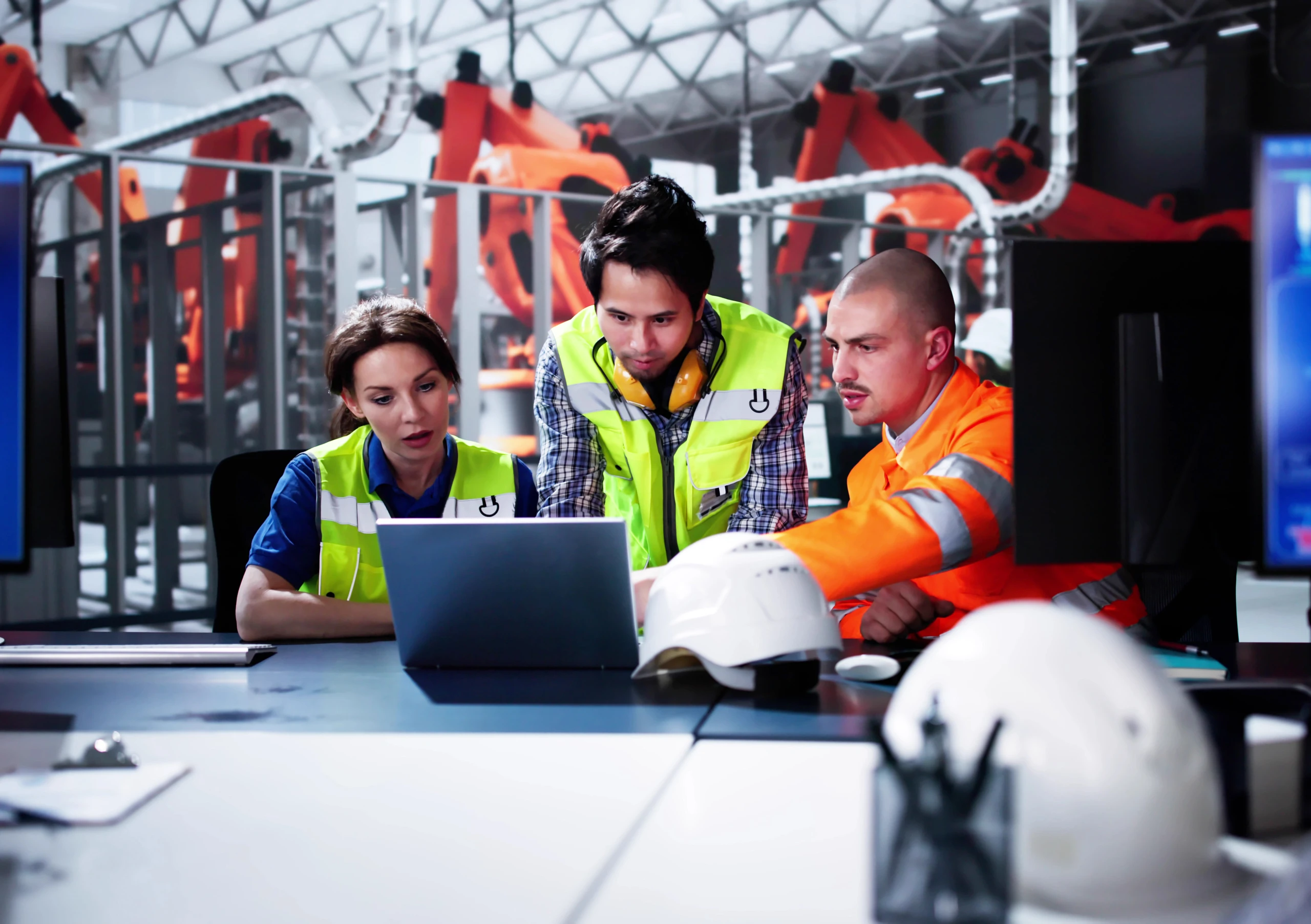 Group of two men and one woman working at computer in a car factory - Andrey Popov / Adobe Stock