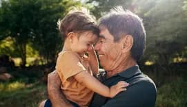 Playful grandfather spending time with his grandson in park on sunny day
