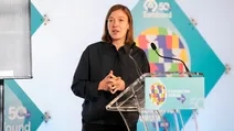 A woman speaks at a podium during the Eurofound 50th Foundation Forum, with a colorful logo and microphone in front of her.
