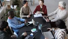 Diverse group of business people sitting at table during briefing meeting in office