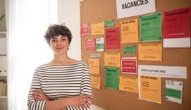 Young woman standing by job vacancies notice board