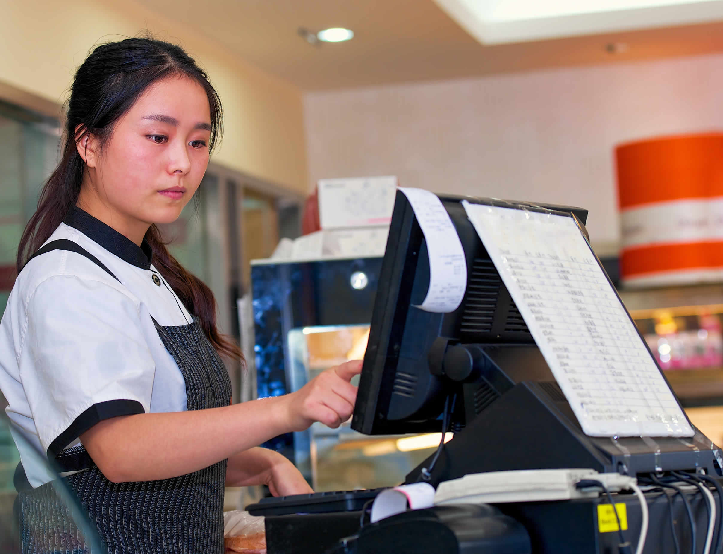 Photo of young café barista at cash register