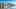 Dublin city along the river with glass buildings, a unique spiral structure, and the Samuel Beckett bridge under a clear blue sky.
