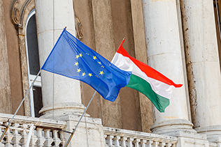 Image of EU and Hungarian flags flying together outside building