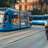 Image of people waiting for tram in city street and man cycling on cycle path